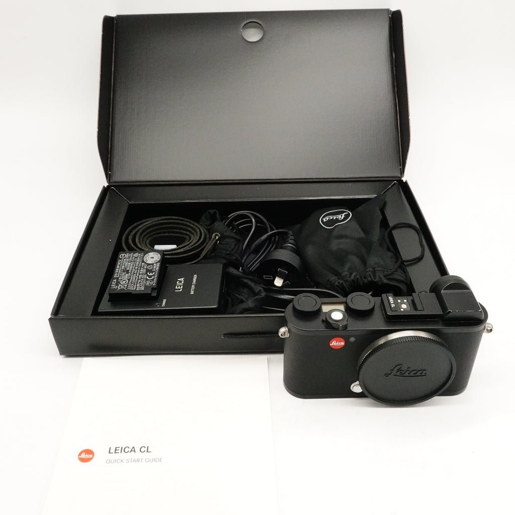 Leica CL camera shown with its open presentation box, accessories including a charger, cable, and dust bag, and a quick start guide on a white background.